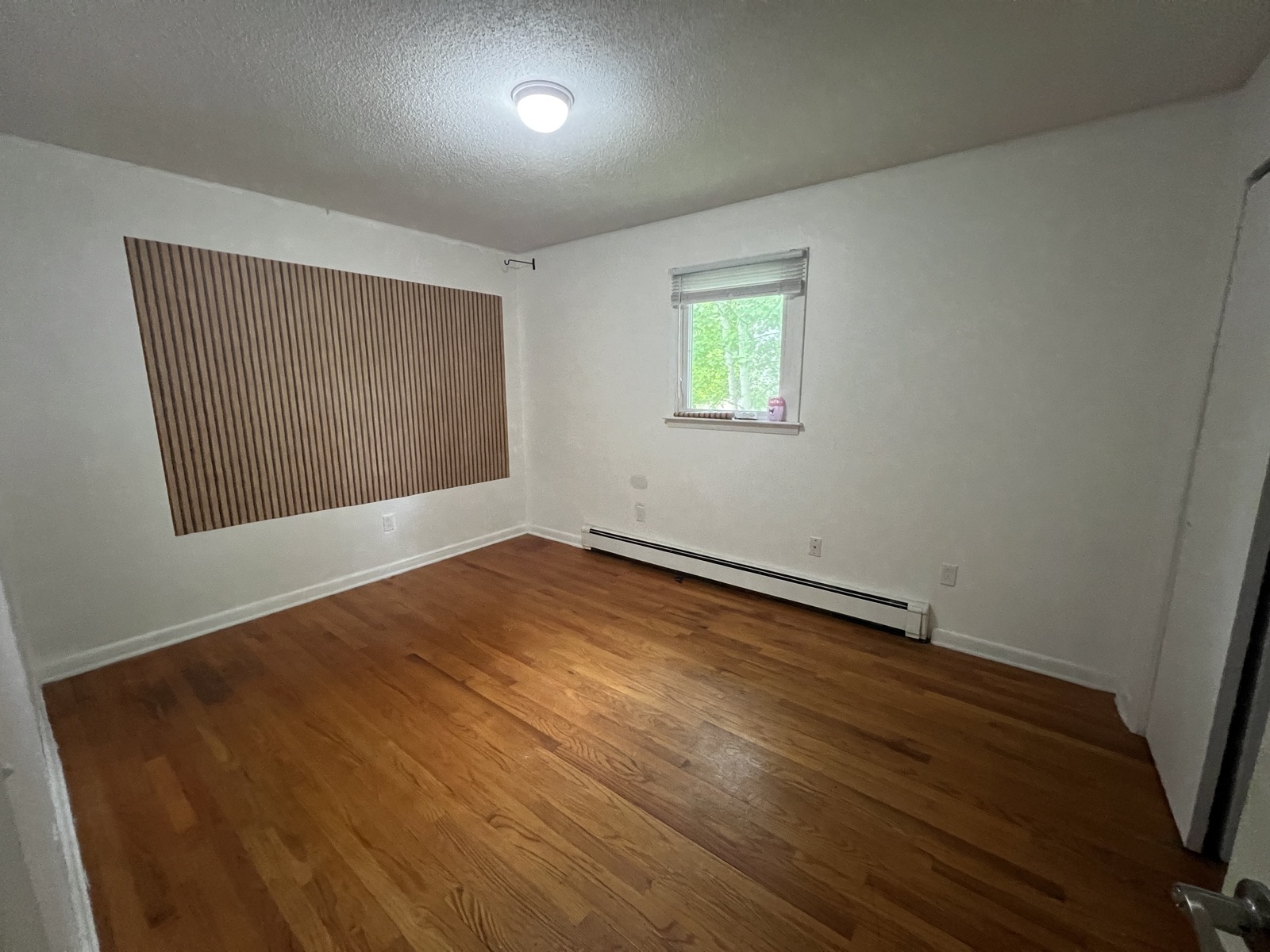 Rosewood Rental bedroom with hardwood floors, window light, and clean walls.