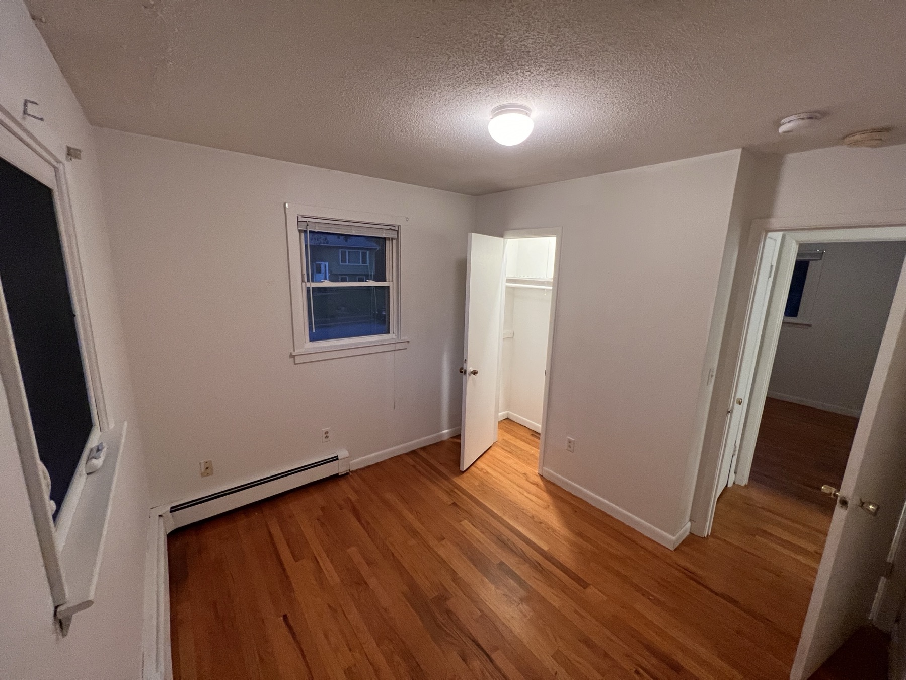 Rosewood Rental additional bedroom view with wall space, wood flooring, and window light.
